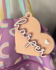 Heart-shaped name tag with 'Harper' on a purple bag with rainbow patterns