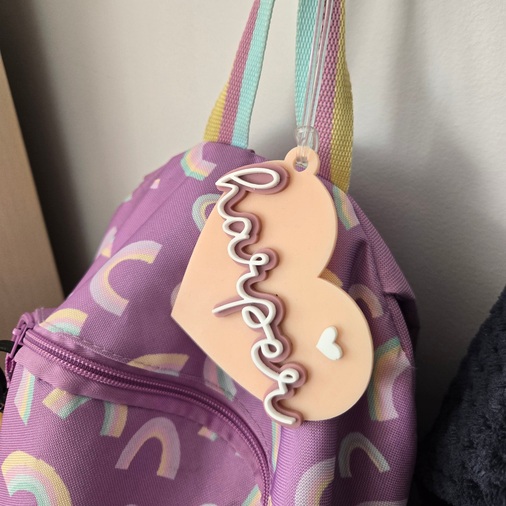 Heart-shaped 'happy' tag on a purple bag with rainbow patterns