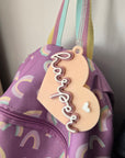 Heart-shaped 'happy' tag on a purple bag with rainbow patterns