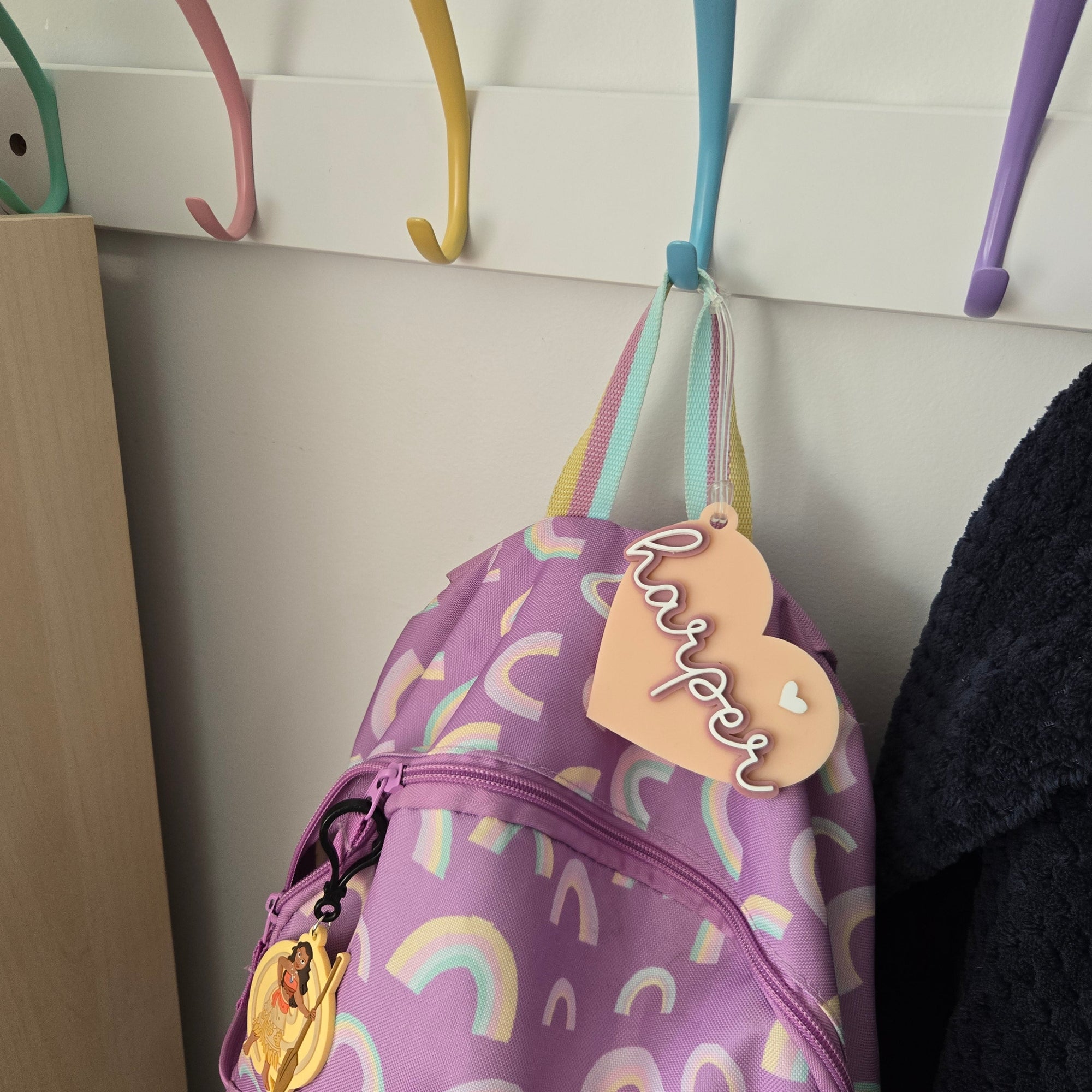 Purple bag with rainbow patterns and a name tag on a light-colored surface