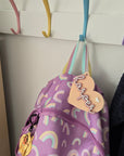 Purple bag with rainbow patterns and a name tag on a light-colored surface