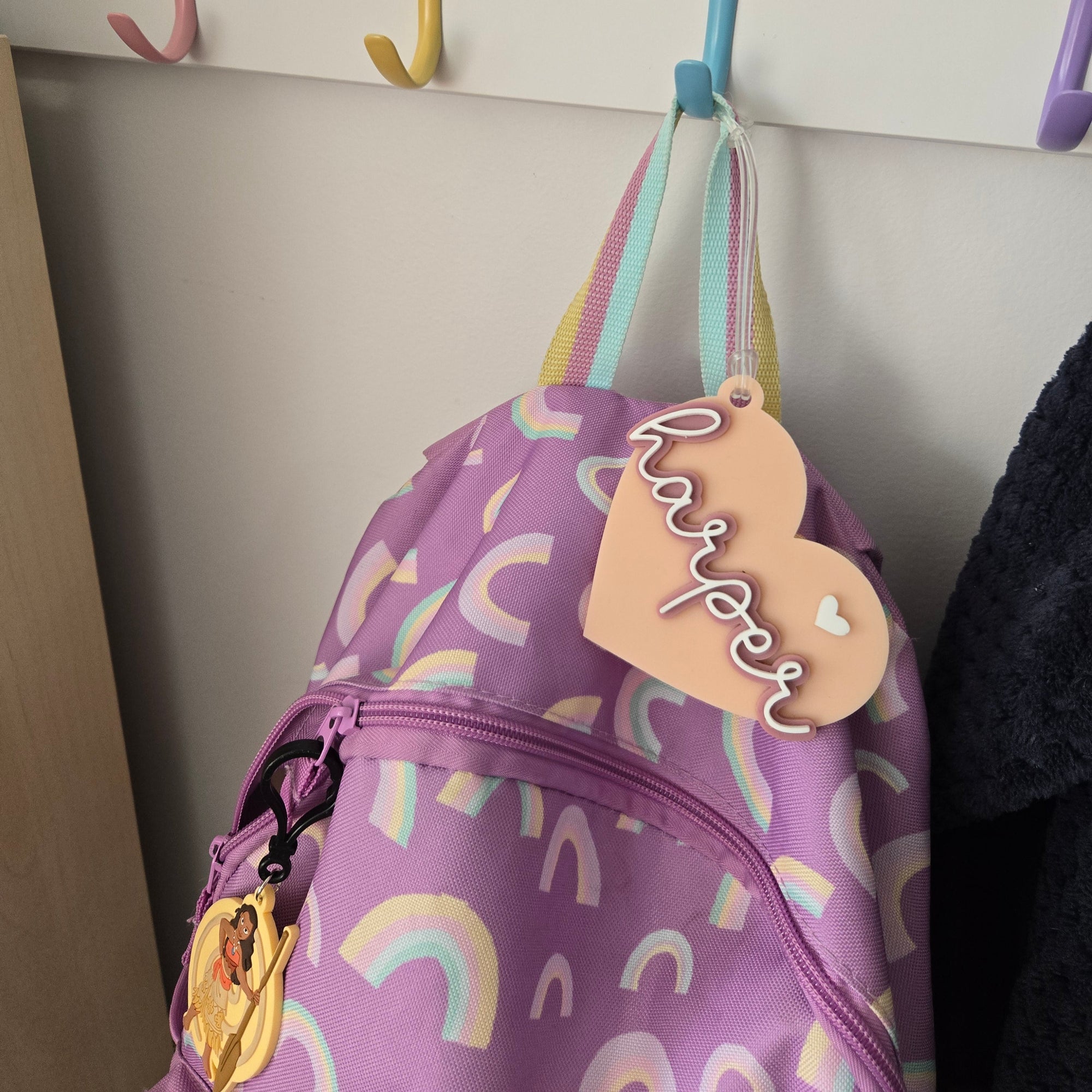 Purple bag with rainbow patterns and a name tag on a light gray background