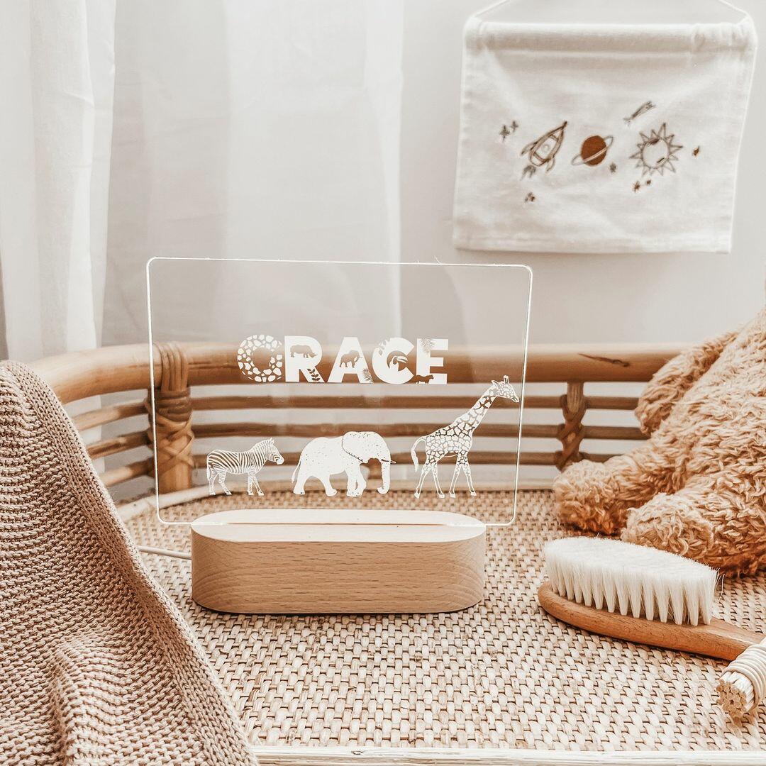 A charming nursery scene showcasing a personalised Warm White Night Light by The Willow Corner in the Safari Animals design. The light, featuring the name 
